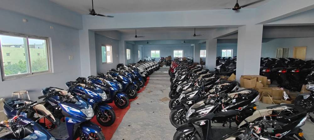 Rows of blue, white, red and black scooters inside the Excon facility
