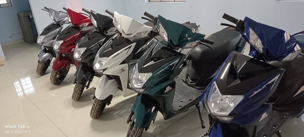 Six Excon electric scooters lined up in grey, red, black, white, green and blue